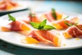 close-up of prosciutto slices between cantaloupe wedges with mint