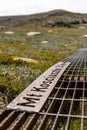 Close-up of public signage on the rusty steel boardwalk connecting the summit of Mount Kosciuszko summit in background& Thredbo