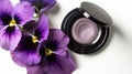 a close up of a purple flower and a black and white eye shadow on a white surface with purple flowers on the side of the Royalty Free Stock Photo