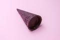 Close up of purple waffle horn filled with cottage cheese in chocolate glaze on pink background, flat lay, diagonally.