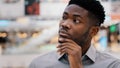 Close-up puzzled concentrated pensive serious african american young man looking away keeps hand on chin thinks solves Royalty Free Stock Photo