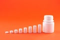 Close up pyramid concept of white pills and bottle on orange background with copy space. Focus on foreground, soft bokeh. Pharmacy Royalty Free Stock Photo