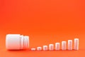 Close up pyramid concept of white pills and bottle on orange background with copy space. Focus on foreground, soft bokeh. Pharmacy Royalty Free Stock Photo