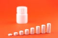 Close up pyramid concept of white pills and bottle on orange background with copy space. Focus on foreground, soft bokeh. Pharmacy Royalty Free Stock Photo