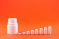 Close up pyramid concept of white pills and bottle on orange background with copy space. Focus on foreground, soft bokeh. Pharmacy Royalty Free Stock Photo