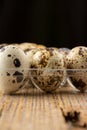 Close-up of quail eggs in transparent plastic egg cup, selective focus, on wooden table, vertical Royalty Free Stock Photo