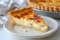 Close-up of Quiche Lorraine slice with bacon, onion and chicken eggs. Baked custard dough served on white plate. Classic