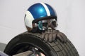 The close up of racing helmet with googles and leather racing gloves on formula tire.