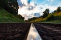 Close up of the railway rails and electric poles and wires in the woodland in sunset time in summer