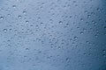 Close up of rain drops on window with blue gray background of dark sky Royalty Free Stock Photo