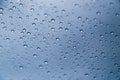 Close up of rain drops on window with blue gray background of dark sky Royalty Free Stock Photo