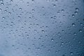 Close up of rain drops on window with blue gray background of dark sky Royalty Free Stock Photo