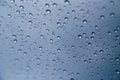 Close up of rain drops on the windshield, front window of a car on a blue gray background of dark sky. Royalty Free Stock Photo