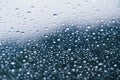 Close up of rain drops on the windshield, front window of a car on a blue gray background of dark sky. Royalty Free Stock Photo