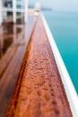 close up of raindrops on a wooden handrail on the deck of a ship