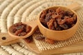 Close-up of raisins in wooden bowl and spoon on wooden chopping board