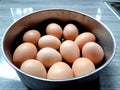 Close-up raw chicken egg group in a stainless steel bowl, and  on blue background. Royalty Free Stock Photo