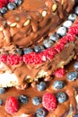 Close up raw healthy vegan cheesecake with chocolate, raspberries, blueberries and nuts. Royalty Free Stock Photo