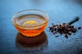 Close up of raw honey in a glass bowl on wooden surface along with powdered rock slat in a black colored spoon.Helps in getting go