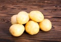 Close up of raw and organic new light brown potatoes on a dark brown wooden table. Summer harvest potato. A heap of baby potatoes.