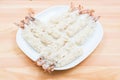 Close-up of raw tempura shrimps in a breaded lay on a white plate that stands on a wooden table. Marine semi-finished Royalty Free Stock Photo