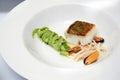 Close-up of a ready-made dish of fish, mussels and seafood in a round plate on a white table in a restaurant before dinner at a Royalty Free Stock Photo