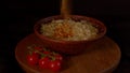 Close up of ready-made instant noodles in plate on tray. Unrecognizable person sprinkles spicy condiment into plate with