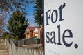 Close up of a real estate sign board with text `for sale` , some suburban houses/Australian homes and pedestrian walkway as