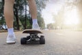 Close up rear view Asian women leg on surf skate or skate board in outdoor Park. Closeup leg wear white sneakers put on surfskate