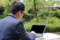 Close up rear view of handsome young business man is working with laptop in public nature background. Royalty Free Stock Photo