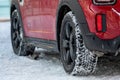 Close up rear view of a red car on parking,, dirty rear wheel tire on snow