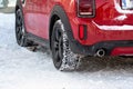 Close up rear view of a red car on parking,, dirty rear wheel tire on snow