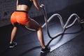 Rear view of tonned woman training with battle rope in cross fit gym Royalty Free Stock Photo