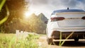 Close-up rear view of a white car with morning light with mountains and sky on the road Royalty Free Stock Photo