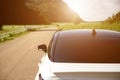 Close-up rear view of a white car with morning light with mountains and sky on the road Royalty Free Stock Photo