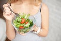 Close-up rear view woman holding bowl of fresh vegetable salad holding fork in hand Royalty Free Stock Photo