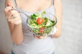 Close-up rear view woman holding bowl of fresh vegetable salad holding fork in hand Royalty Free Stock Photo