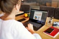 Close-up rear view of young business or student woman working at cafe with laptop computer, typing, looking at screen