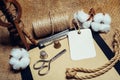 Close up rectangle tag on clipboard with vintage paper, beside cottons balls, rope and vintage spinning wheel. Mock up cotton