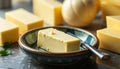 A close-up of a rectangular block of butter on a ceramic saucer, accompanied by a