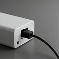 A close-up of a rectangular, white electronic device with a black cable plugged into a Royalty Free Stock Photo