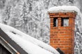 Close up on red brick chimney in winter scenery with snow on a rooftop