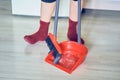 Close up of a red broom and plastic dustpan on the floor with unrecognisable woman with copy space. Concept of cleaning Royalty Free Stock Photo