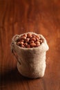 Close-up of red-brown peanuts Arachis hypogaea in a standing jute bag over wooden brown background Royalty Free Stock Photo