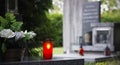 Close up of a red burning candle and flower decoration on the grave. Royalty Free Stock Photo