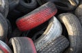 Close up of red car tires with tread in a pile of used tires