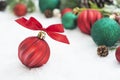 Close up red christmas ball, bauble with ribbon and green fir branches, pine cones, on white snow background. Winter holidays. Royalty Free Stock Photo