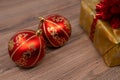 Close-up of a red christmas bulbs with a gift box in background on a wooden table