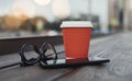 Close up of red coffee cup, mobile phone and glasses. Royalty Free Stock Photo