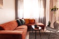 Red corner sofa with cushions standing against the window in warm living room interior. Real photo Royalty Free Stock Photo